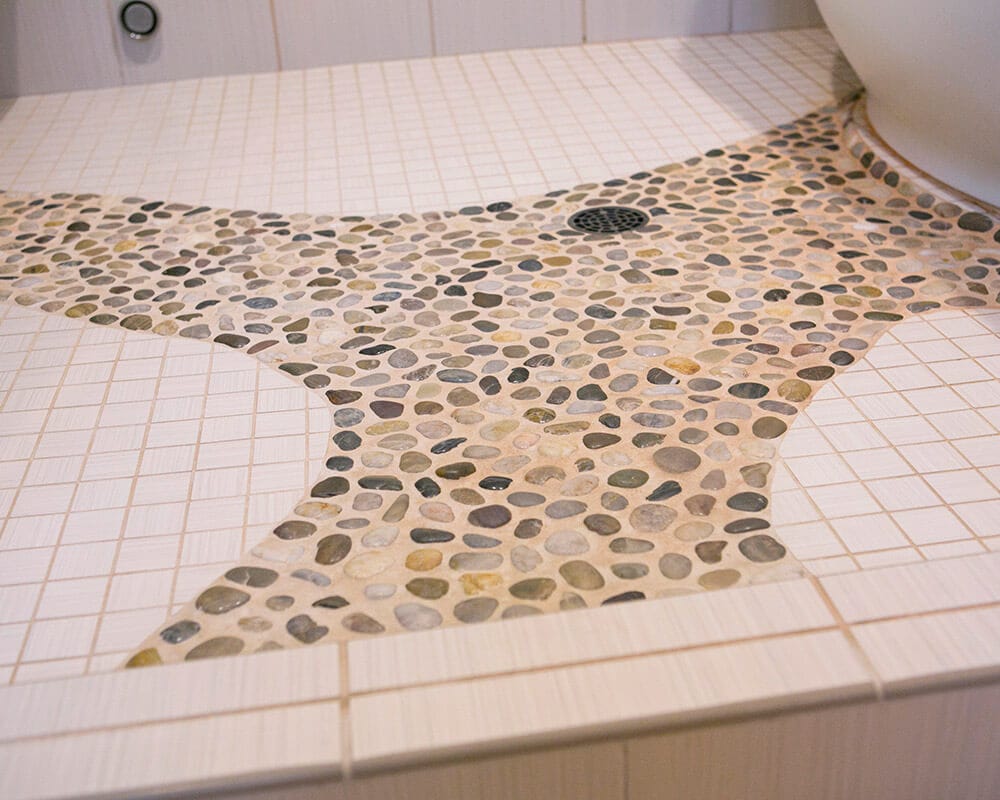 Custom bathroom remodel by TDS Design Build using locally sourced river rocks set in the floor of the steam shower to create a path to the tub and built in shower bench.