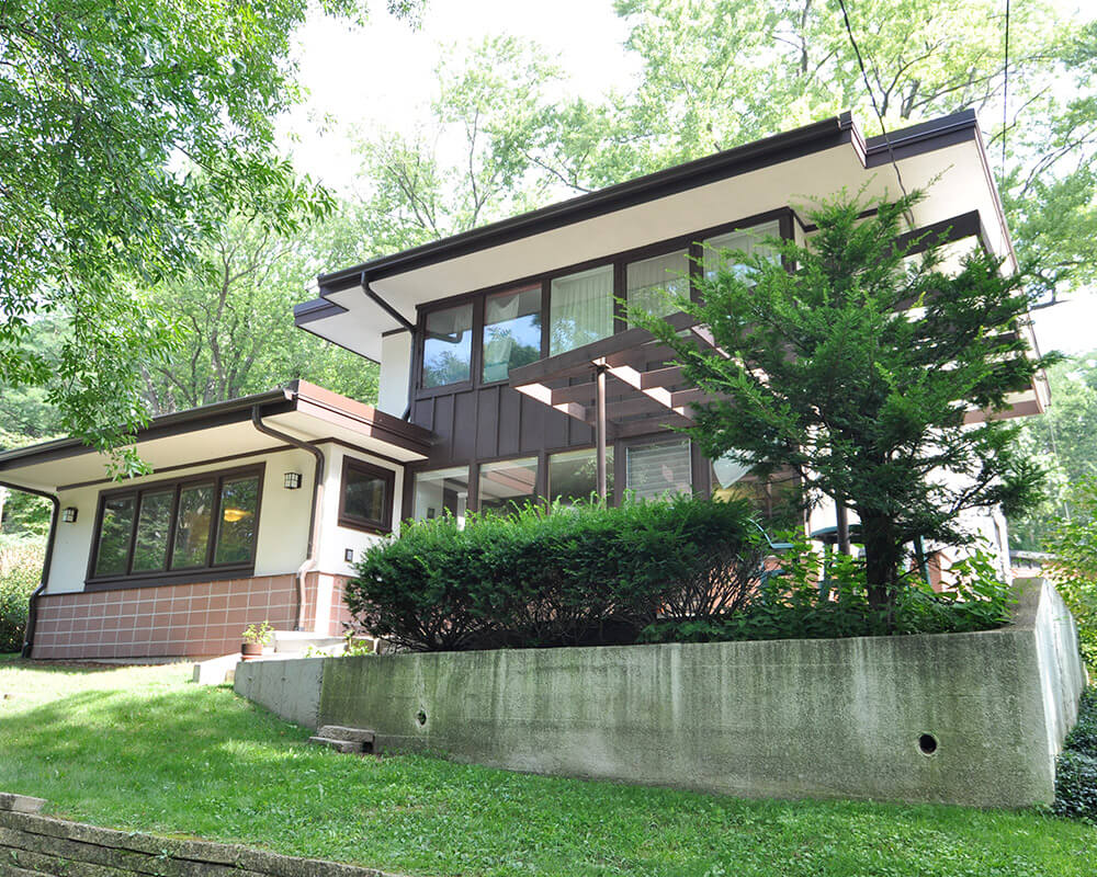 Home addition and exterior remodeling with copper roofing, a bay window and a distinctive sunroom addition adds indoor-outdoor space to the rear of the house by TDS Design Build.