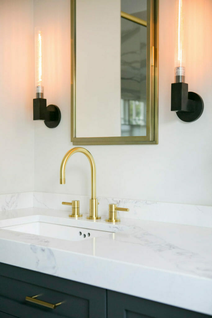 Ensuite bathroom remodel with brass fixtures, marble tiled shower and bathtub, painted Woodharbor cabinets, and marble tile in Maple Bluff, Wisconsin by TDS Design Build.
