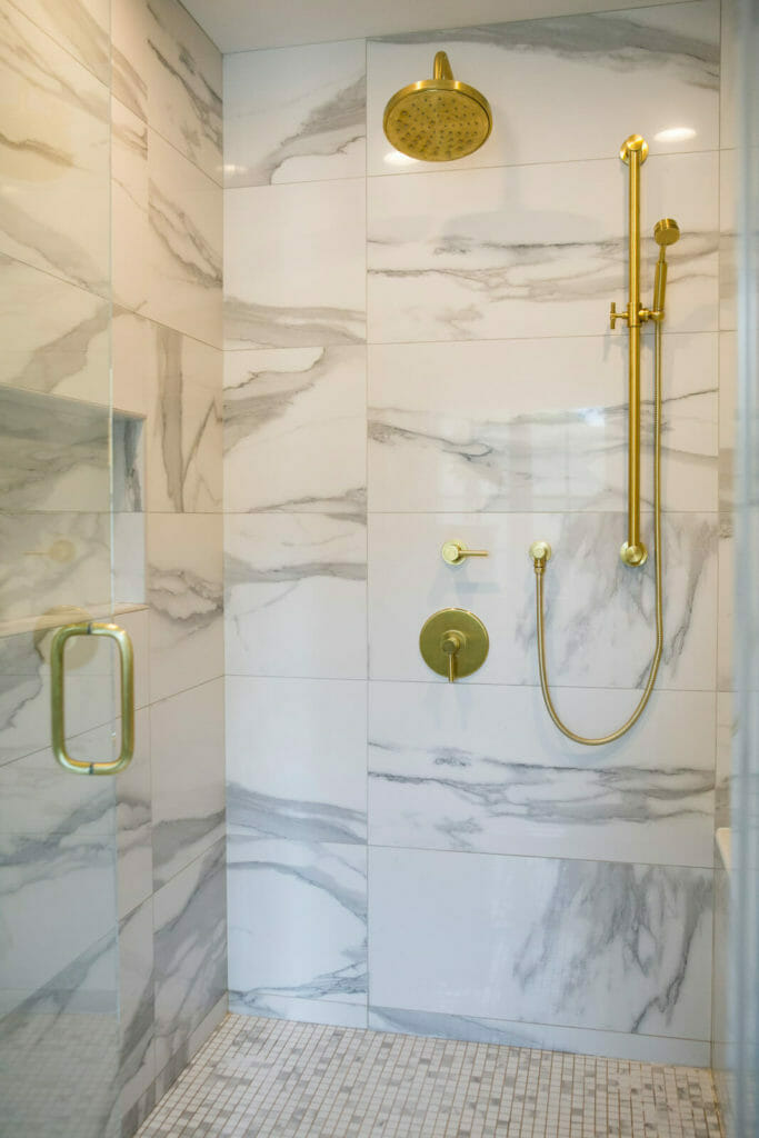 Marble shower with modern brass faucets for this bathroom remodel in Maple Bluff, Wisconsin by TDS Design Build.
