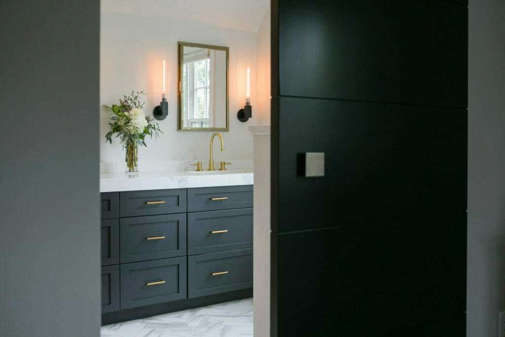 Ensuite bathroom remodel with brass fixtures, marble tiled shower and bathtub, painted Woodharbor cabinets, and marble tile in Maple Bluff, Wisconsin by TDS Design Build.