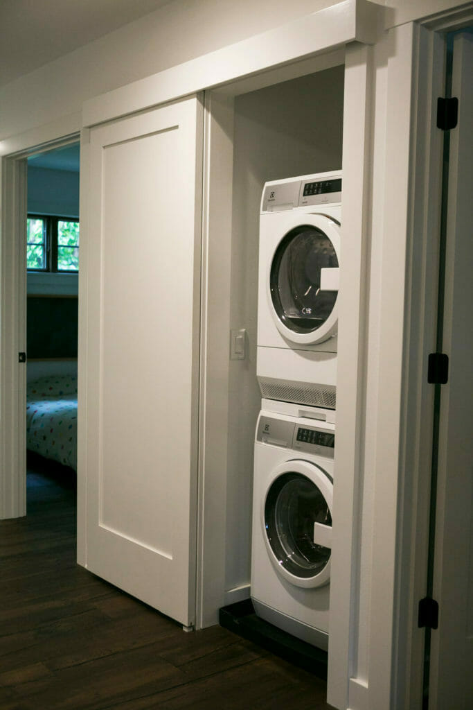 A stacked washer and dryer and a sliding door optimize the space in this 1,000 square foot modern whole house remodel in Monona, Wisconsin by TDS Custom Construction.