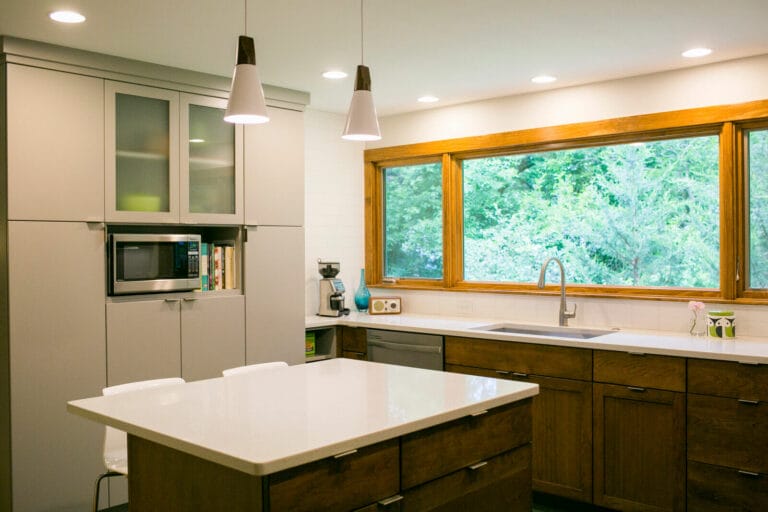 Quartz countertops, Woodharbor painted and walnut cabinets, with modern accents, create a fresh kitchen remodel by TDS Design Build.