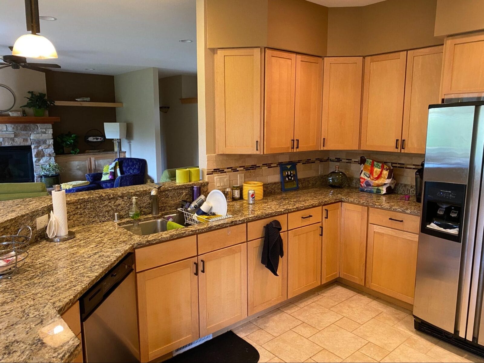 Modern kitchen with wooden cabinets, granite countertops, stainless steel appliances, and a view into a cozy living area.