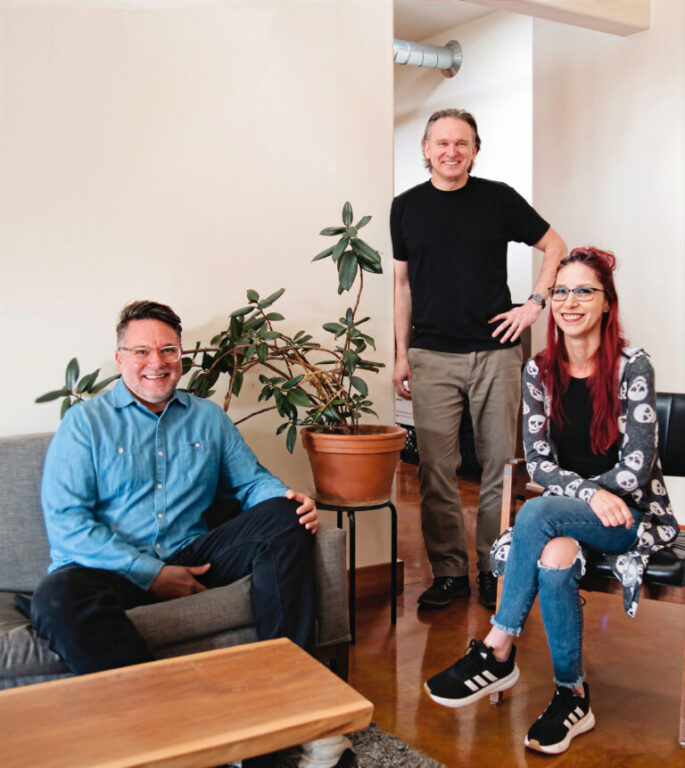 Three people pose in a modern office