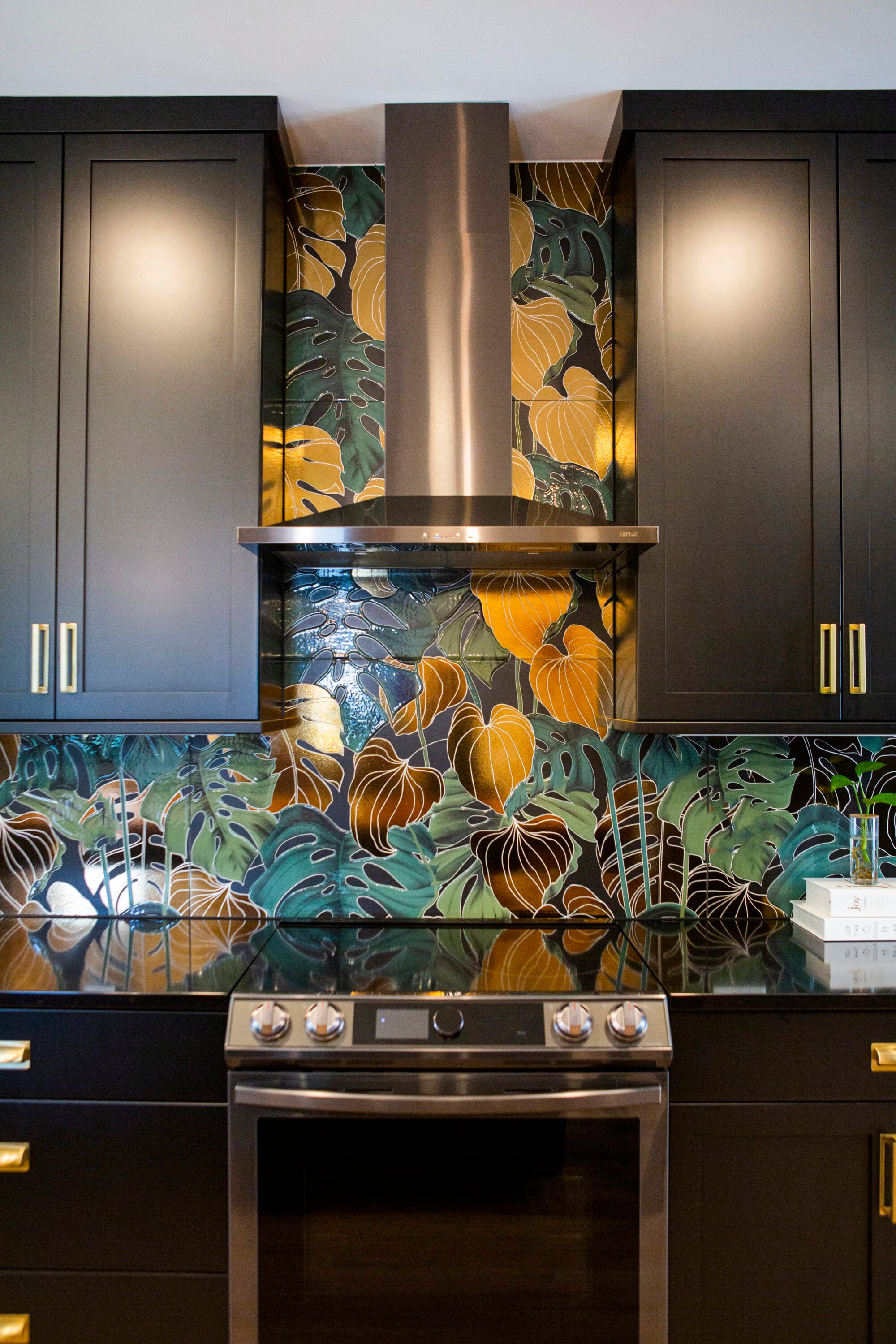 Modern kitchen with black cabinets and a tropical leaf patterned backsplash.