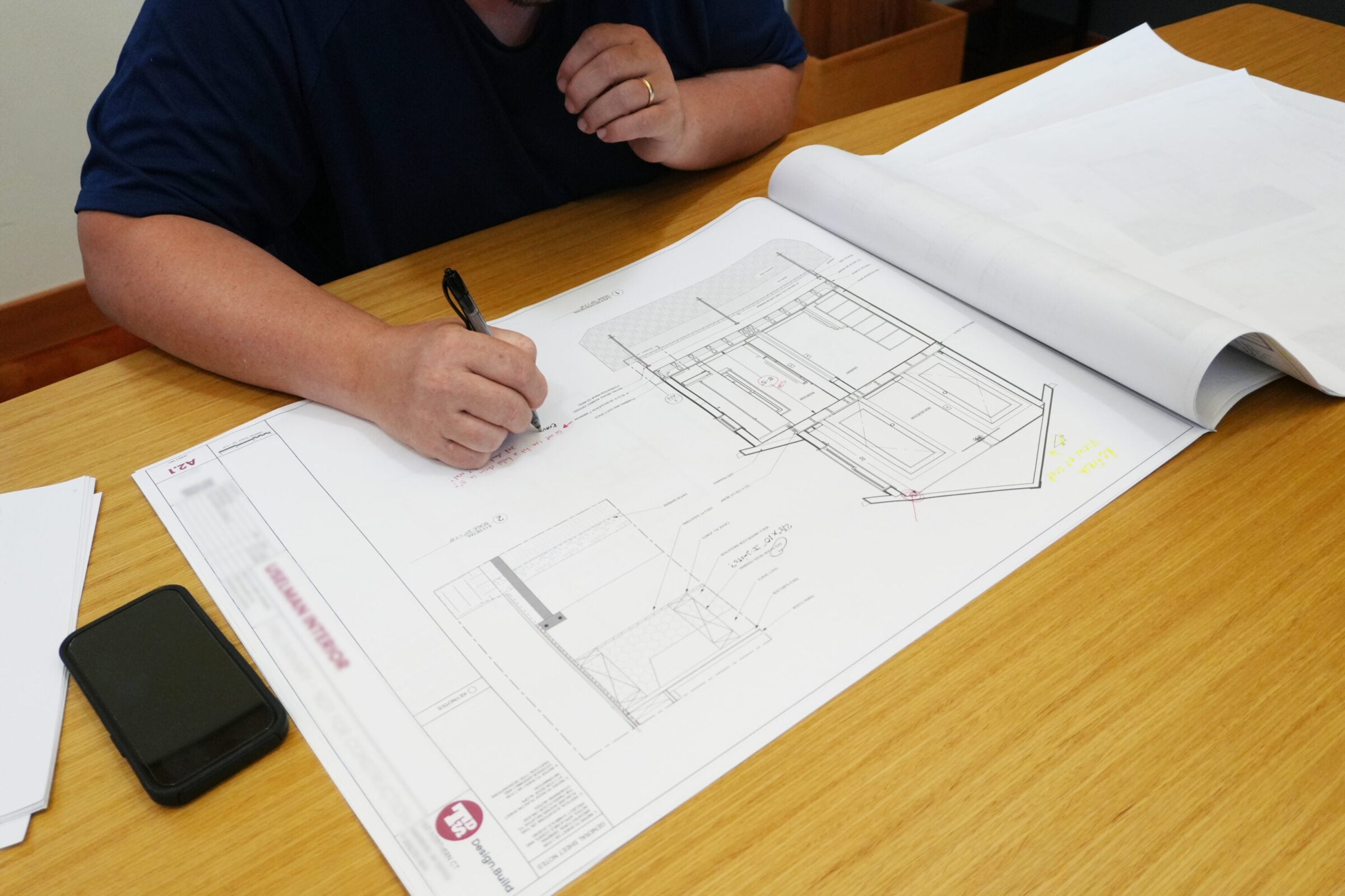 Person reviewing architectural blueprints and making notes.